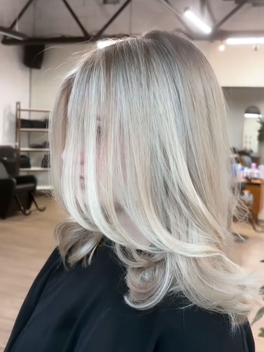 Side view of a woman with layered platinum blonde hair in a salon setting
